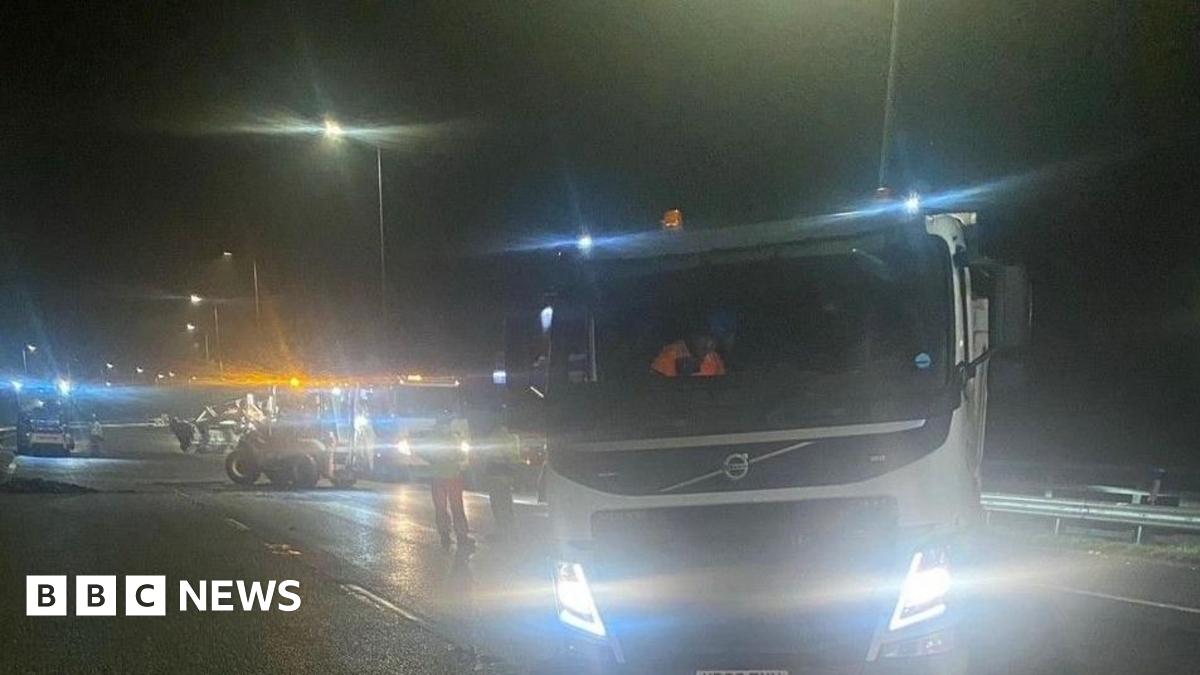 A picture taken in darkness shows a number of pieces of machinery including large lorries and diggers with their lights on on what appears to be a section of motorway