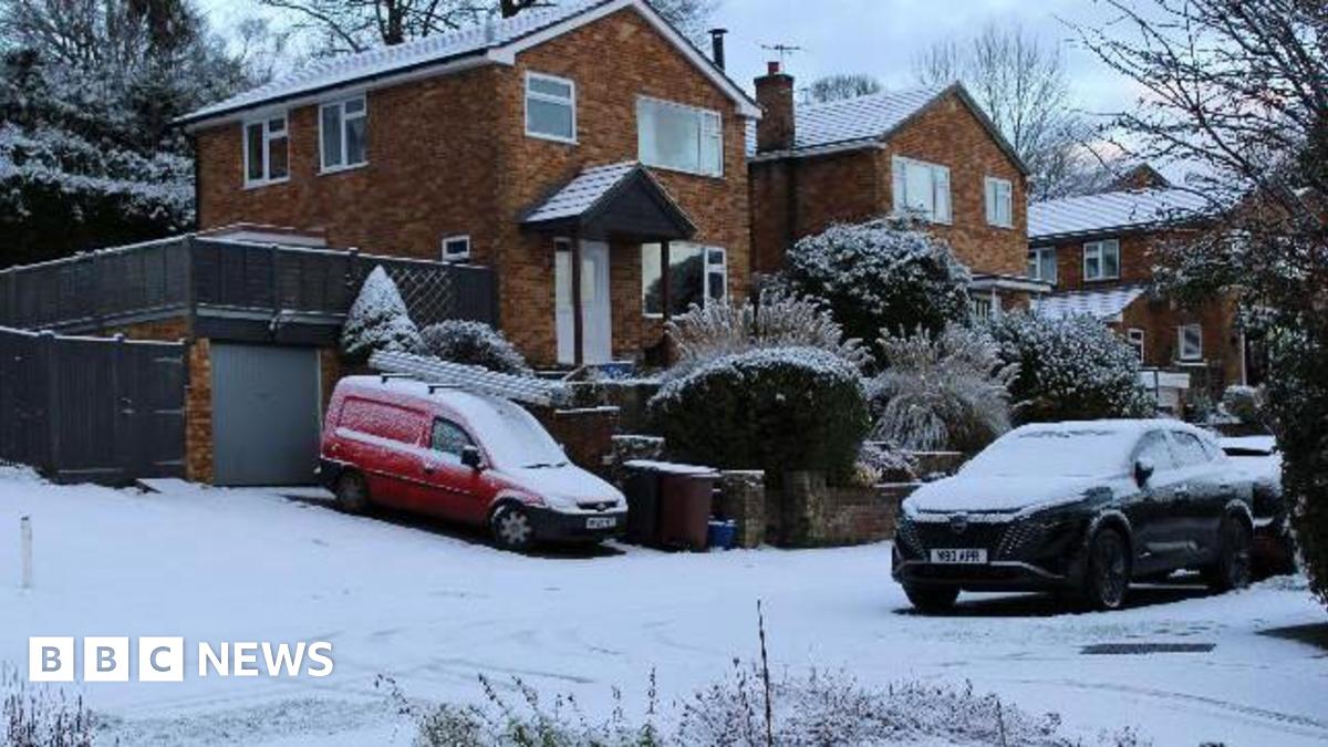 Snowy road and cars and houses in an urban area