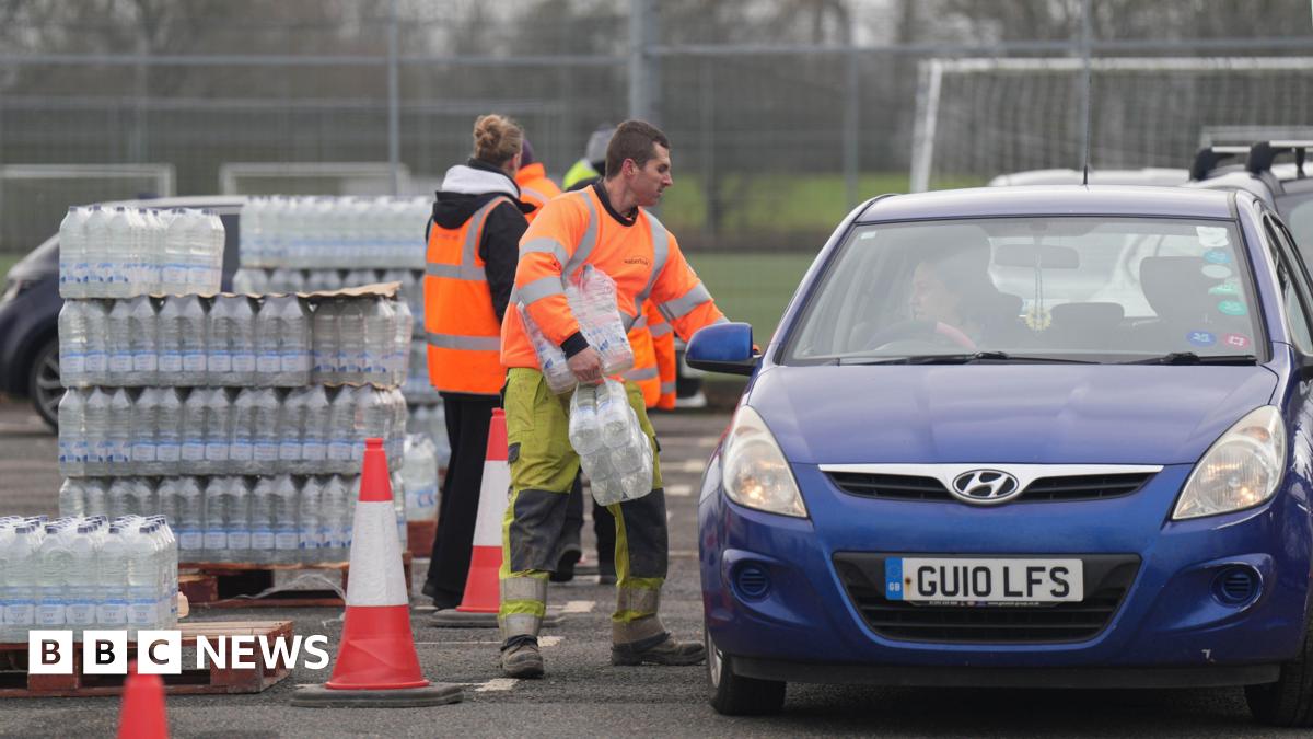 South East Water workers in hi vis hand out bottled water to drivers at East Grinstead Rugby Club.