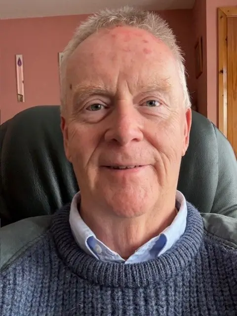 Robert Owens Robert Owens, a 71-year-old man. He has short grey hair and is wearing a navy knitted jumper over a light blue shirt.