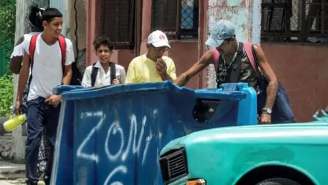 Getty Images A man rummages through a dumpster in Havana, Cuba. Photo: 15 July 2025