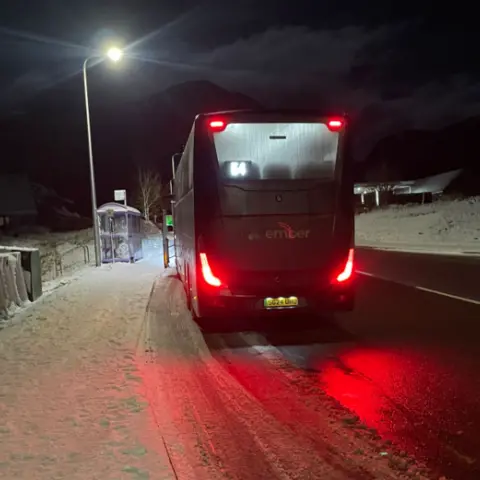 Glencoe Mountain Rescue Team the back of a bus next to a bus stop on a snow-covered road
