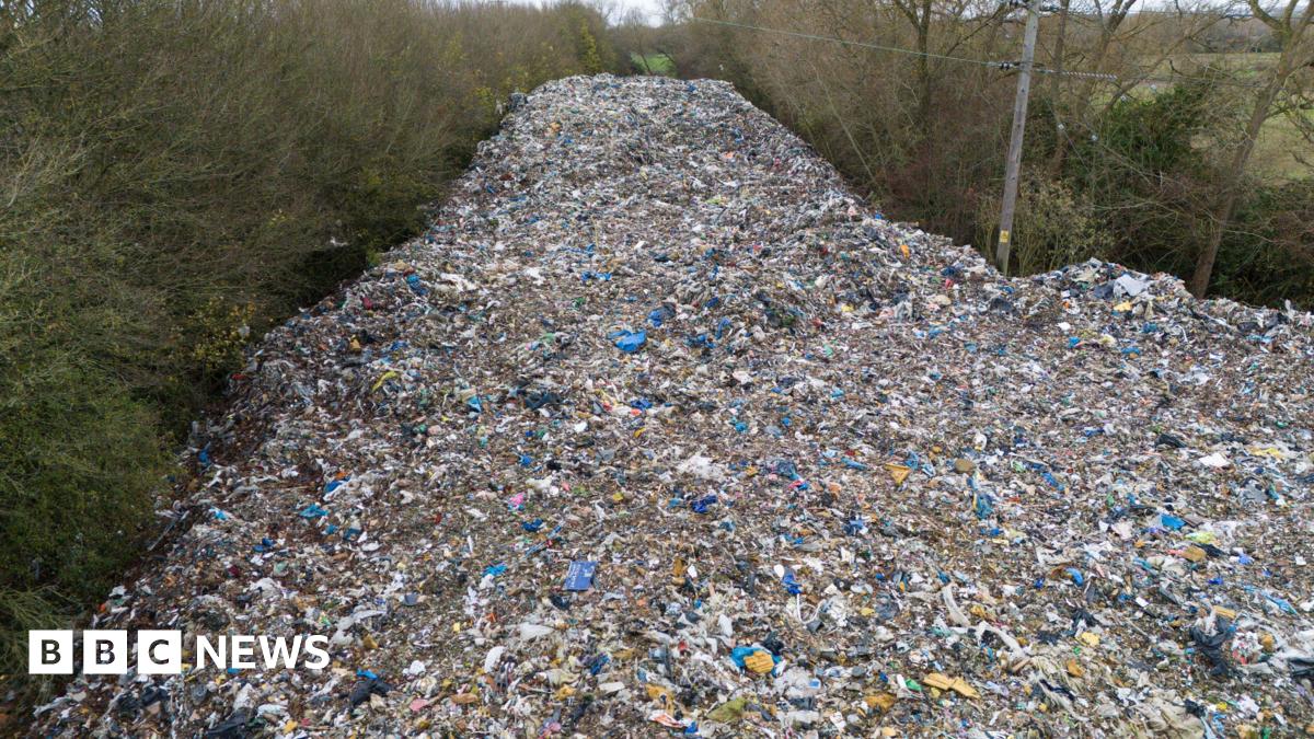 An aerial shot of the dumped waste, stretching out in a road-like line into the distance and surrounded on both sides by trees