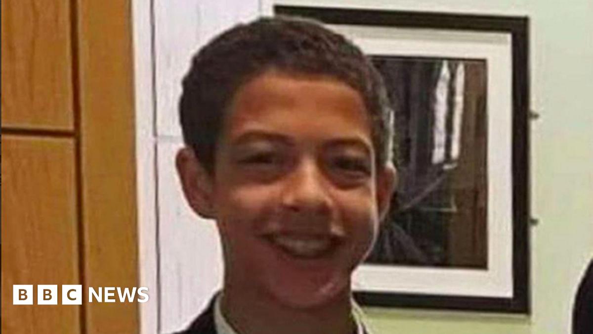 Close shot of a dark haired boy, smiling at camera. He is wearing braces on his teeth.