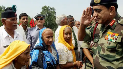 Getty Images Vice Chief of Army Staff Lt.General Deepak Kapoor (R) speaks with widows of fallen 'C' Company Indian soldiers after a ceremony at India Gate in New Delhi, 07 September 2007. The soldiers were honouring those of 'C' Company of the 13th Battalion Kumaon Regiment of the Indian Army who were killed at the Rezangla Post in the Chushul sector of Ladakh during the 1962 war with China. 'C' company were renamed 'Rezangla Company' in honour of the 114men out of a total of 124 who lost their lives. India Gate which stands in the centre of the Indian capital,was built in the memory of more than 90000 Indian soldiers who lost their lives during the Afghan Wars and World War I. The Vice Chief of Army Staff Lt.General Deppak Kapoor flagged off a yatra which will journey through the Indian state of Haryana from where many of the men hailed. AFP PHOTO/RAVEENDRAN (Photo credit should read RAVEENDRAN/AFP via Getty Images)