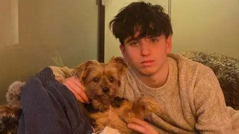Laetitia Brodard-Sitre/Facebook Arthur Brodard sits on a sofa petting a dog