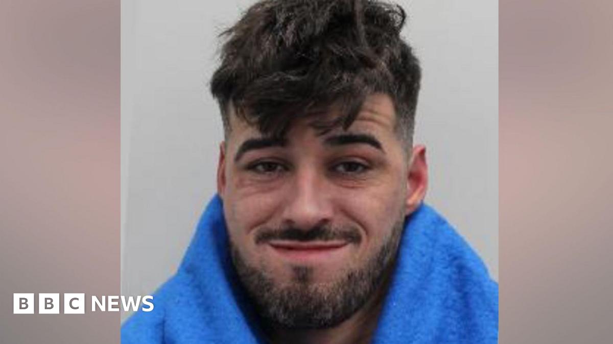 Custody image of Anthony Gilheaney, a man with short, dark, messy hair, facial hair, wearing a smirking expression.