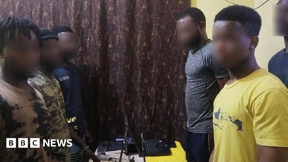 Five men stand over laptops on a table with their hands behind their backs.  The victims were found in their respective apartments, operating laptop computers.