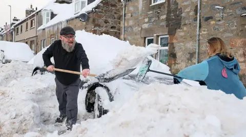 Getty Images People clear their cars after heavy snowfall on 5 January 2026 in Dufftown, UK. 