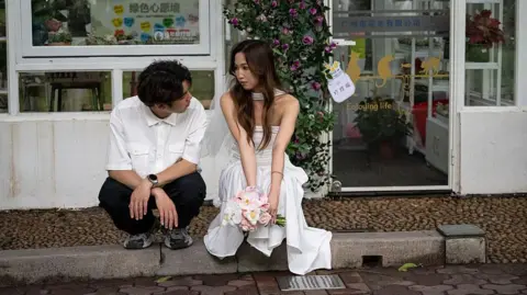 Getty Images A couple takes photos outside the Civil Affairs Bureau on May 20, 2025 in Guangzhou, Guangdong province of China. 