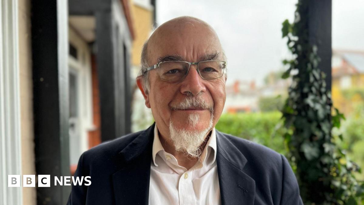 Anthony Sheppard, the chair of Claygate Parish Council's planning committee, looks straight at the camera. He is wearing a white shirt and a dark suit jacket, and has a small white beard.