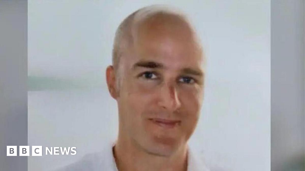 A head and shoulders shot of Alexander Cashford shows a balding man who is smiling.