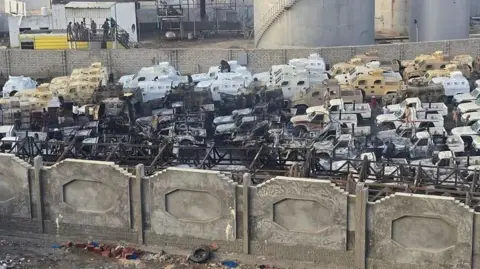 AFP Burned-out military vehicles and pick-up trucks following a Saudi-led coalition air strike in Mukalla, southern Yemen (30 December 2025)