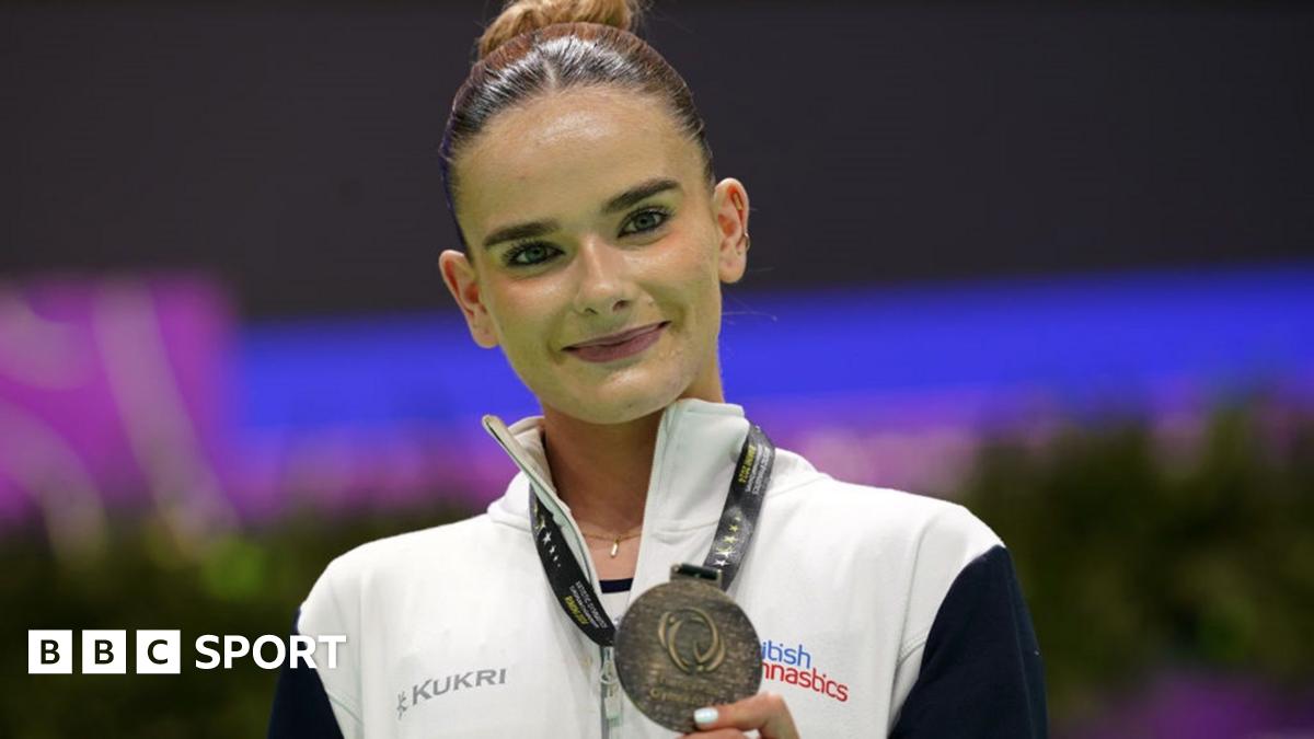 Alice Kinsella does a split leap on beam