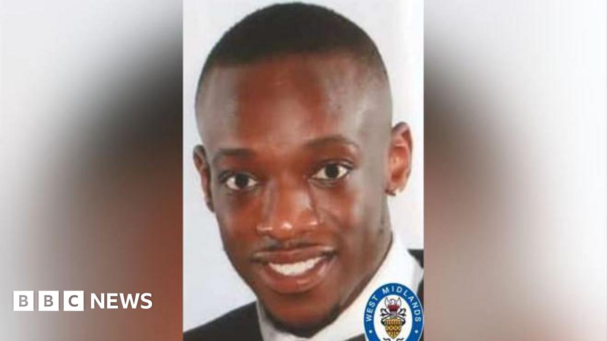 A man with short dark hair and a black collared top