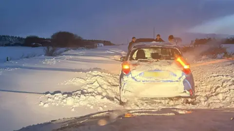 Fubar News A car stuck in a road with drifting snow