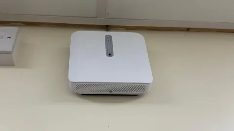 A square white box is fitted to the wall in a toilet in Wales High school with a sensor that detects vaping within the space