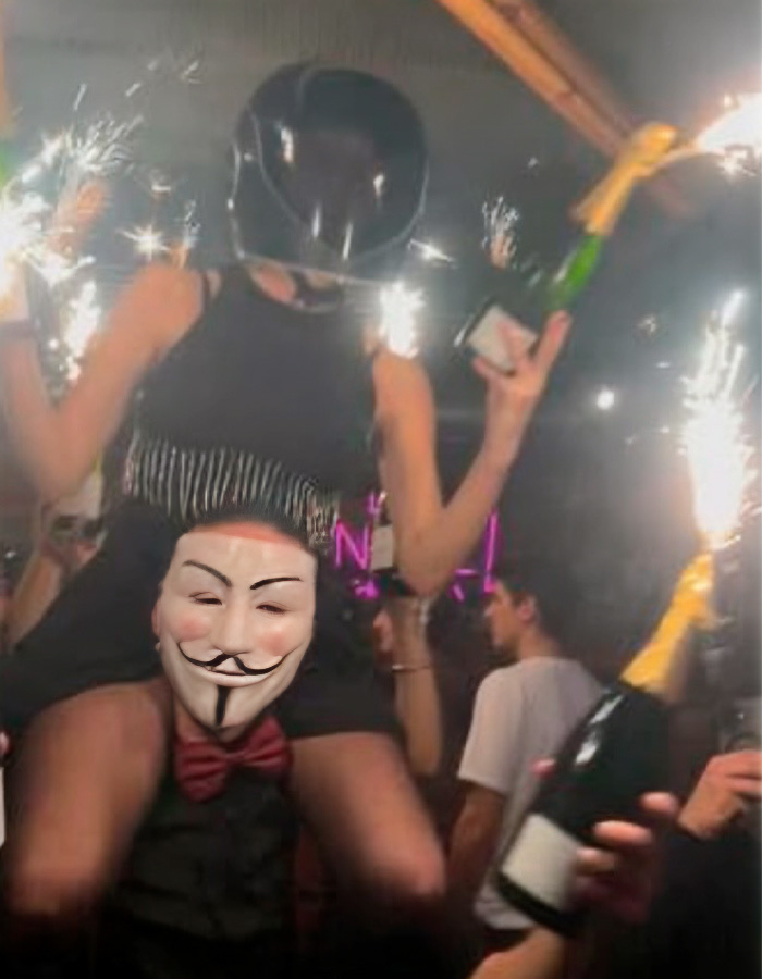 Waitress in a helmet holding sparklers and champagne bottles at a crowded party linked to the Swiss ski resort fire fate. Waitress in a helmet holding sparklers and champagne bottles at a crowded party linked to the Swiss ski resort fire fate.