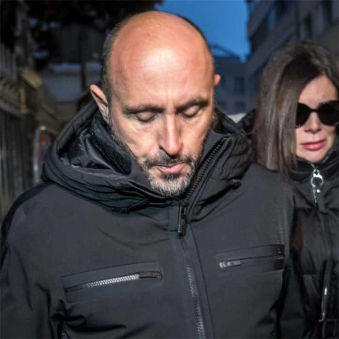 Man in black jacket and woman with sunglasses walking outside, related to fate of waitress in Swiss ski resort fire case. Man in black jacket and woman with sunglasses walking outside, related to fate of waitress in Swiss ski resort fire case.