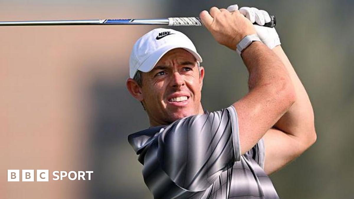 Rory McIlroy watches his shot as he holds a club above his head