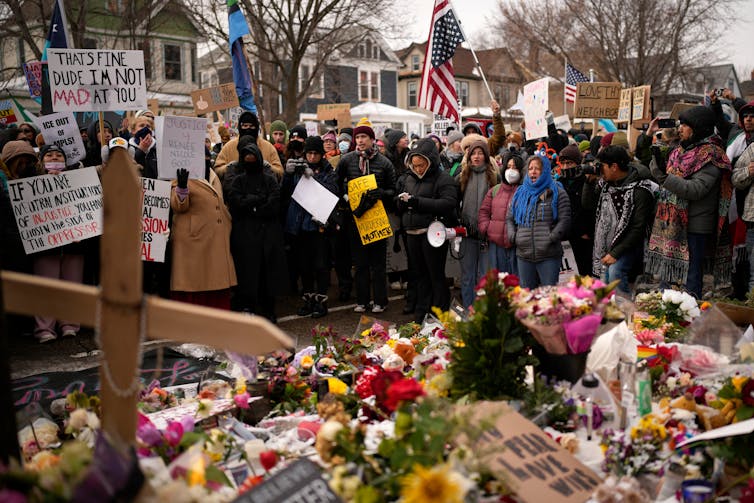 People hold signs and gather around a vigil.