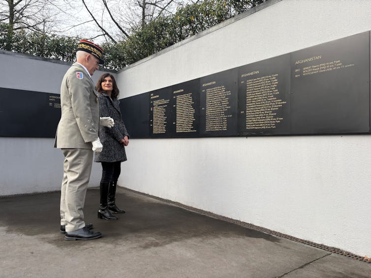 A French defense official and general inspect the names inscribed on a memorial to French dead in Afghanistan.