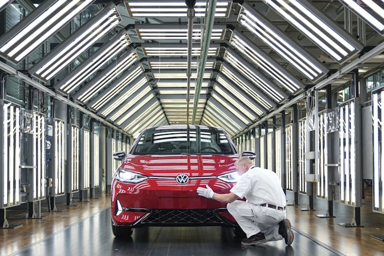 An employee of the German car manufacturer Volkswagen checks an electric car inside a factory