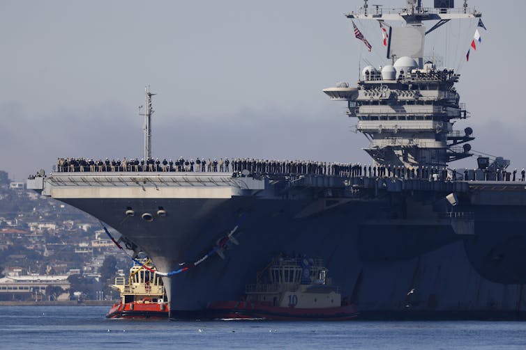 Men and women line the deck of a large ship.