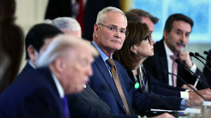 Darren Woods sits among oil executives, looking toward Donald Trump during a meeting in the White House East Room.