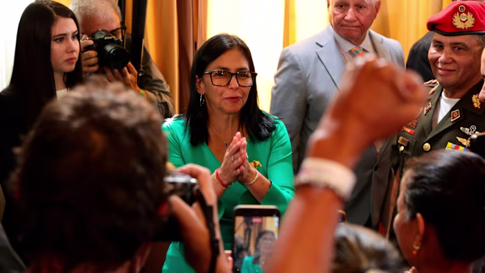Delcy Rodriguez clasps her hands and smiles among supporters and officials