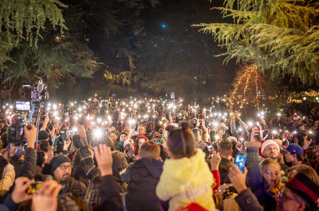 At the Altadena Christmas Tree Lane lighting, cell phone lights are held up during a moment of silence honoring the 19 people who died in the Eaton Fire.