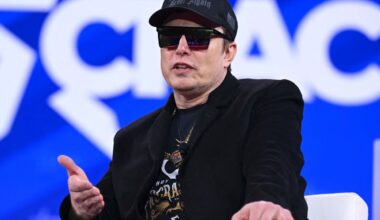 Elon Musk on stage at CPAC in Maryland with sunglasses on and a MAGA hat