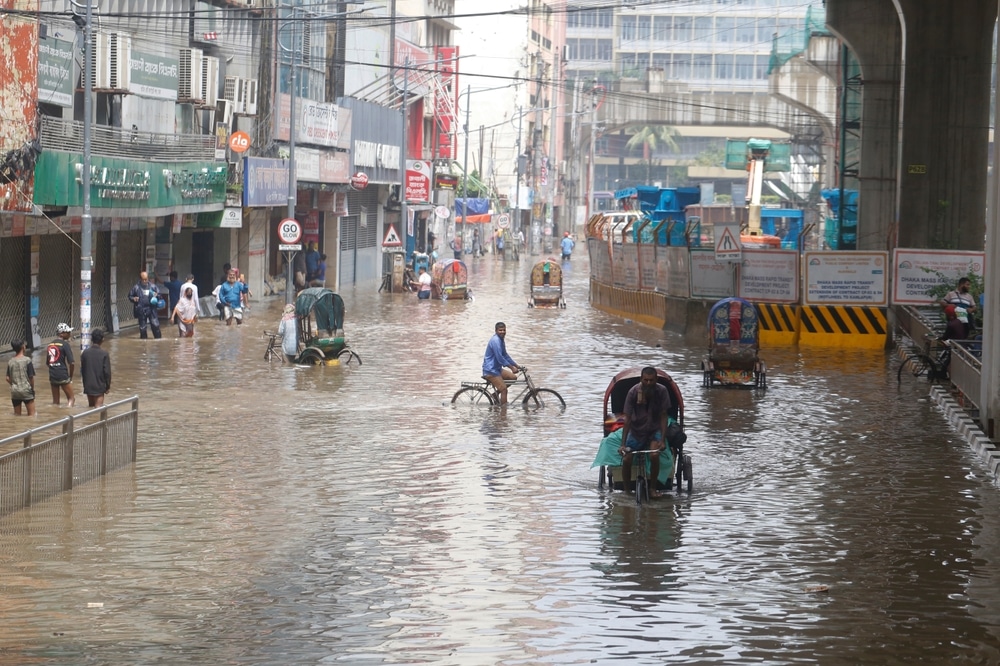 People Make Their Way Through A Flooded Street After Heavy Monsoon Rainfall In Dhaka