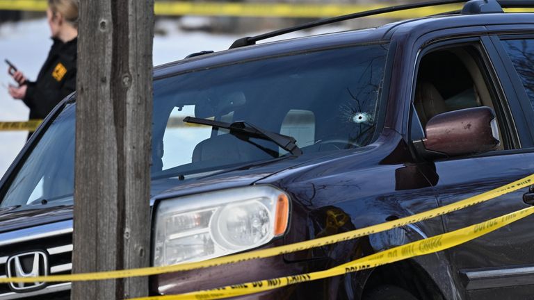 A bullet hole is seen in the windshield as law enforcement officers work at the scene of the shooting. Source: AP