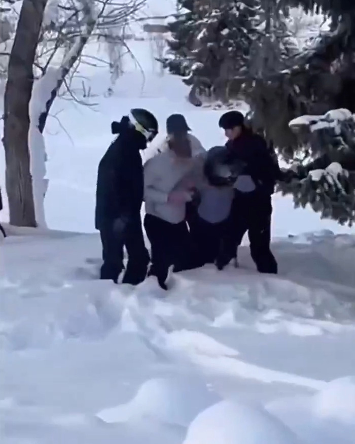 Skiers helping injured person in snowy forest after snow leopard attack caught on viral video.