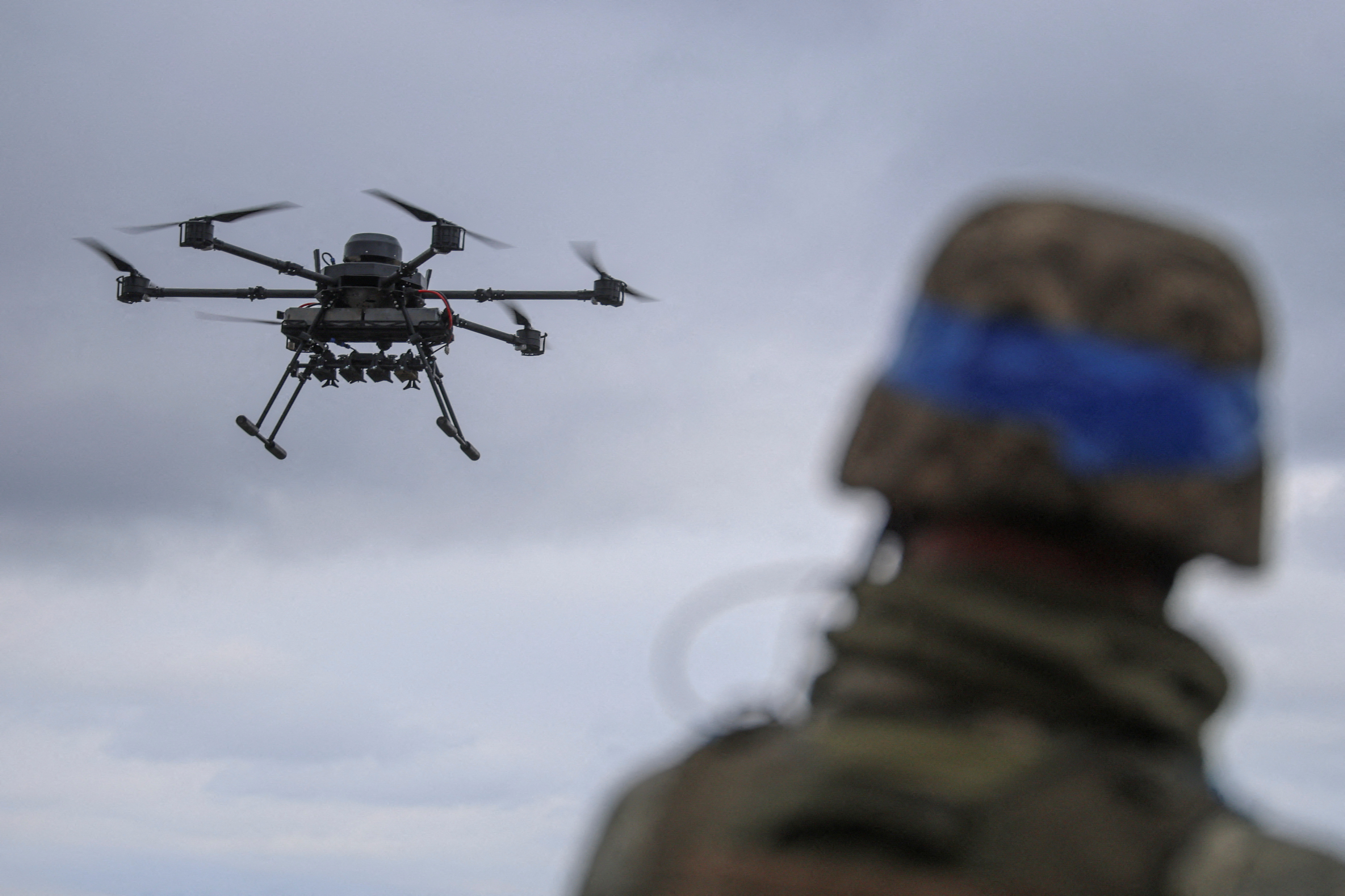 A Ukrainian serviceman watches a heavy drone in flight near a front line in Donetsk region.