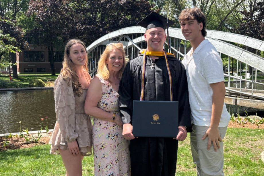 Rhonda Dorgan posing with her two children and a graduate in cap and gown, holding a diploma.