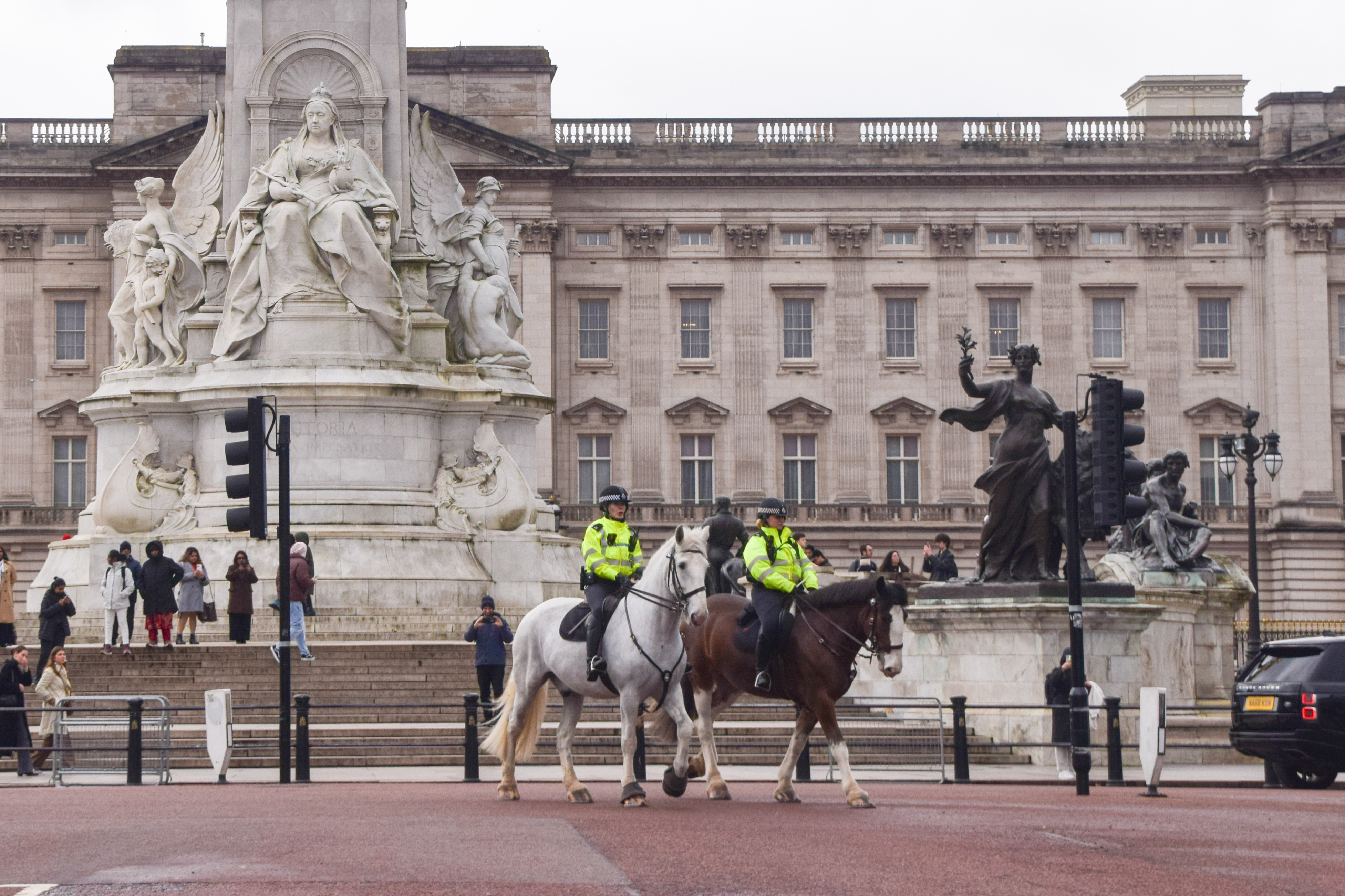Two mounted police officers on horseback patrol outside Buckingham Palace.