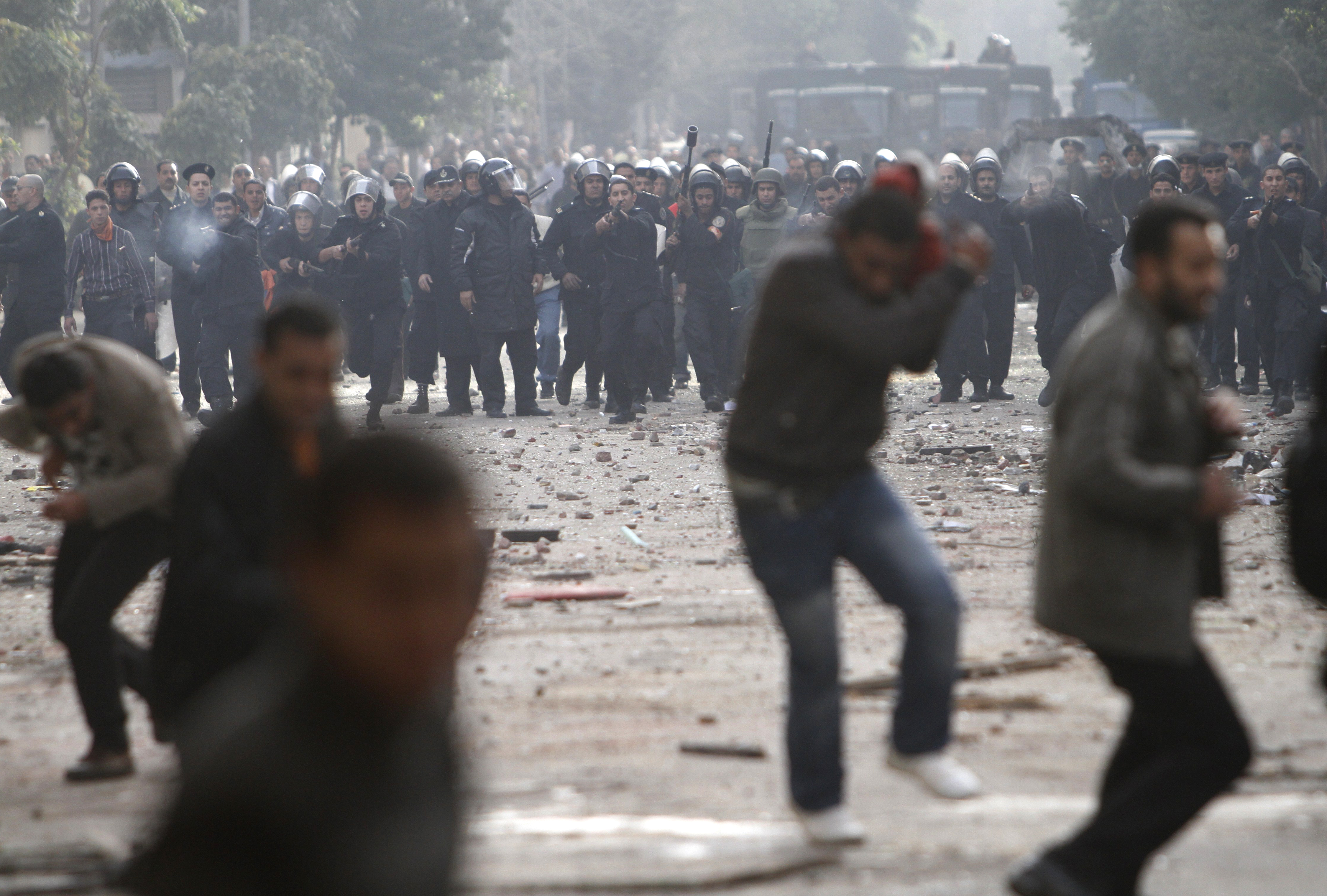 Egyptian protesters clash with riot police on a dusty street in Cairo.
