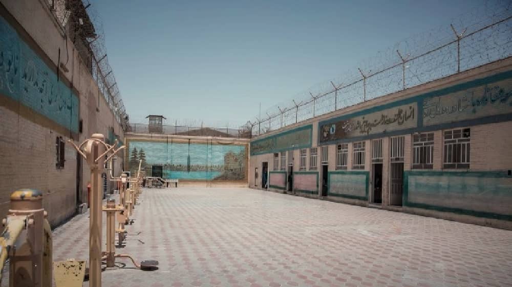 Courtyard of Yazd Prison in central Iran with exercise equipment and murals.