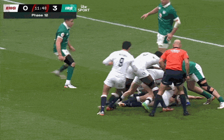 Rugby players in white and green jerseys grappling on a field with a scoreboard showing "ENG 0 IRE 3".