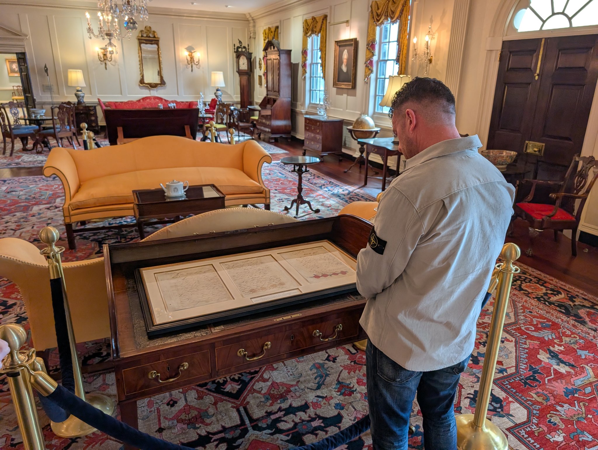 A man viewing historical documents in a glass display case inside the Department of State.