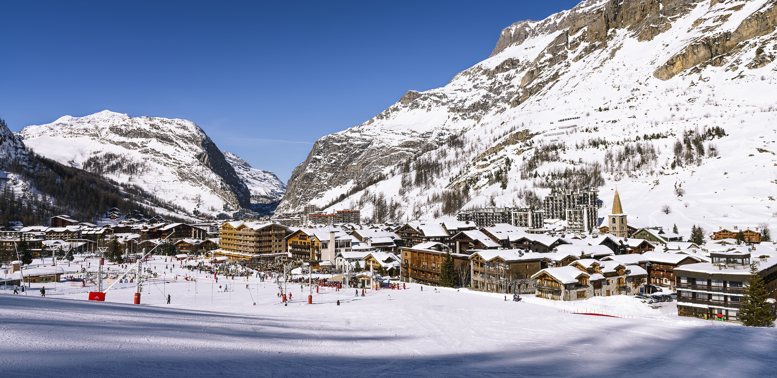 A snowy ski resort town nestled between large snow-covered mountains.