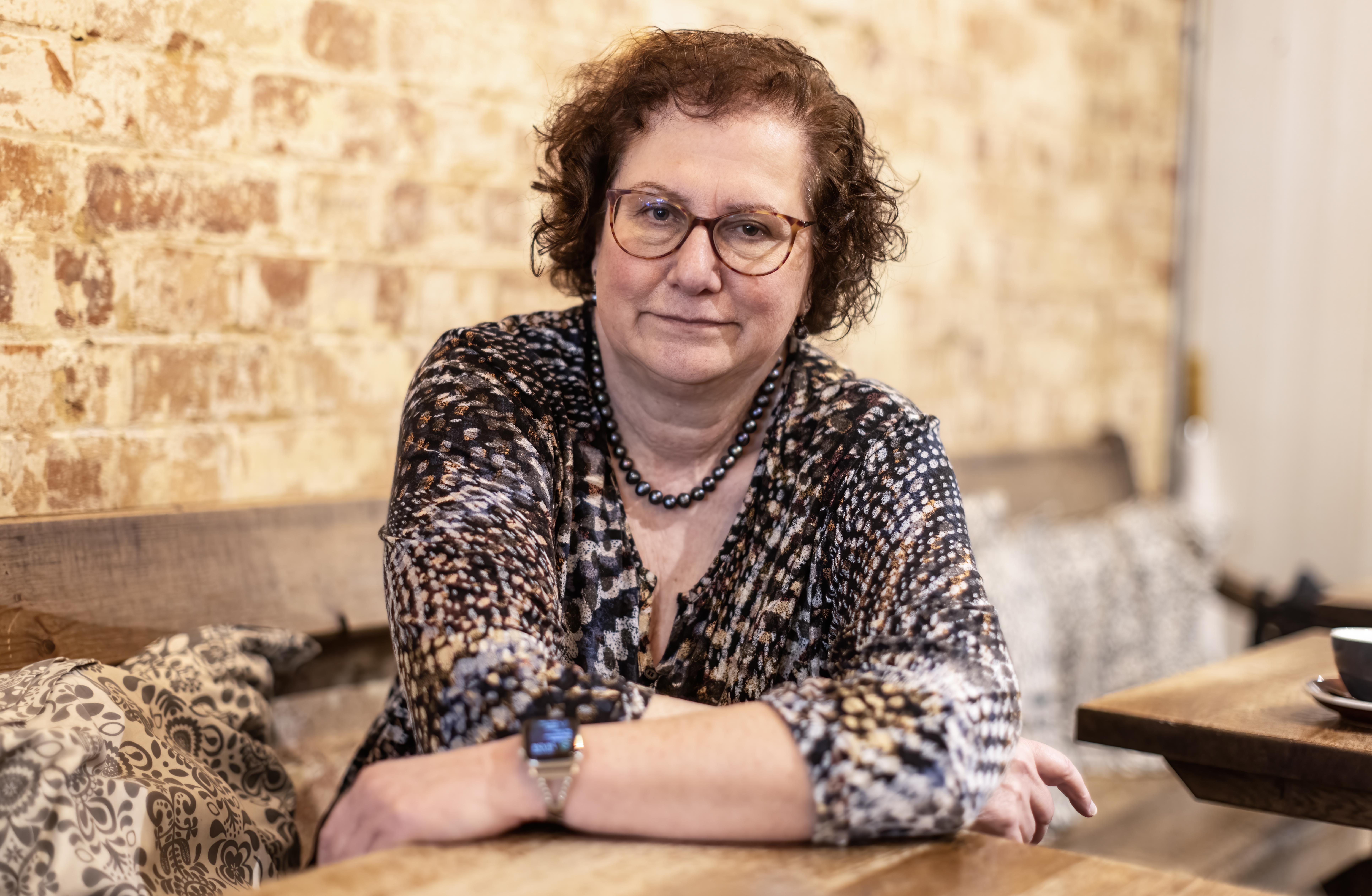 Dr. Hilary Cass, author of the Cass report, seated at a cafe table.