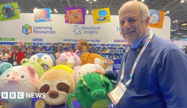 A man poses in front of a display of stuffed animals.