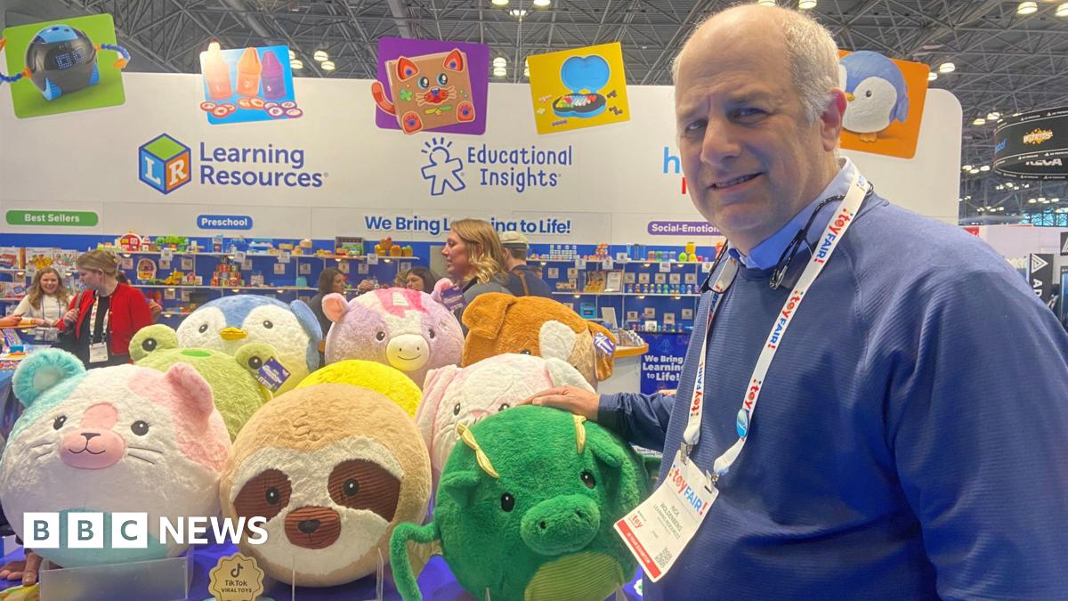 A man poses in front of a display of stuffed animals.
