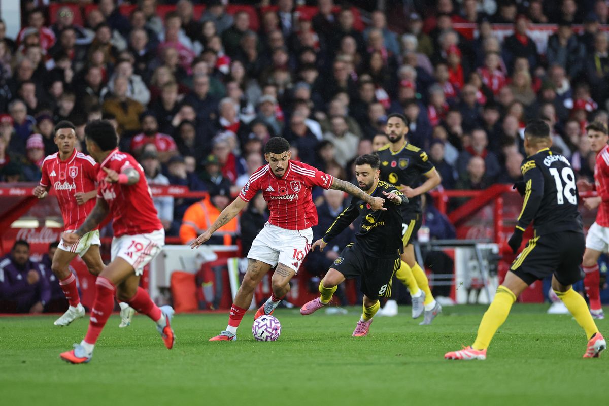 Morgan Gibbs-White of Nottingham Forest runs with the ball under pressure from Bruno Fernandes of Manchester United