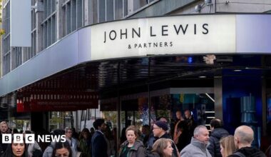 The sign of the Oxford Street John Lewis shop in London with a bustling street below it