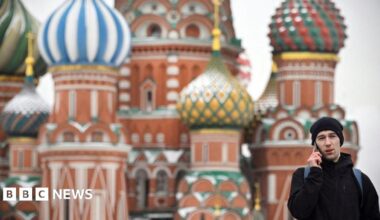 Man in black talking on the phone in Russia's Red Square with Saint Basil's Cathedral in the background