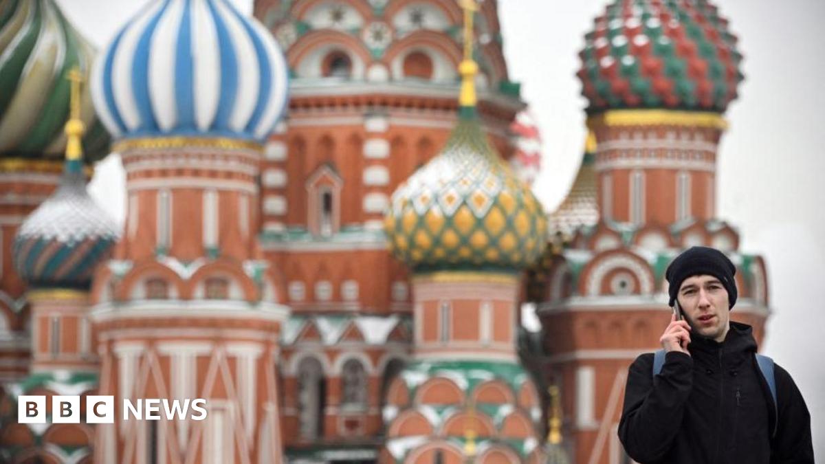 Man in black talking on the phone in Russia's Red Square with Saint Basil's Cathedral in the background